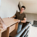 Two men carrying a table down the stairs.