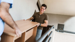 Two men carrying a table down the stairs.