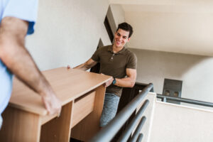 Two men carrying a table down the stairs.