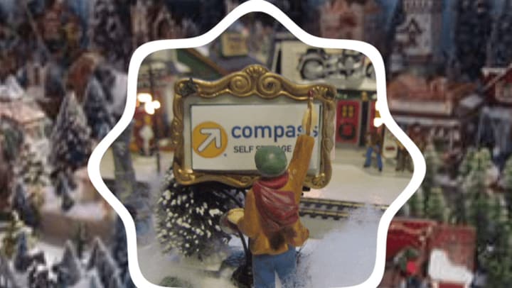 Christmas figurine looks at mini Compass Self Storage sign.