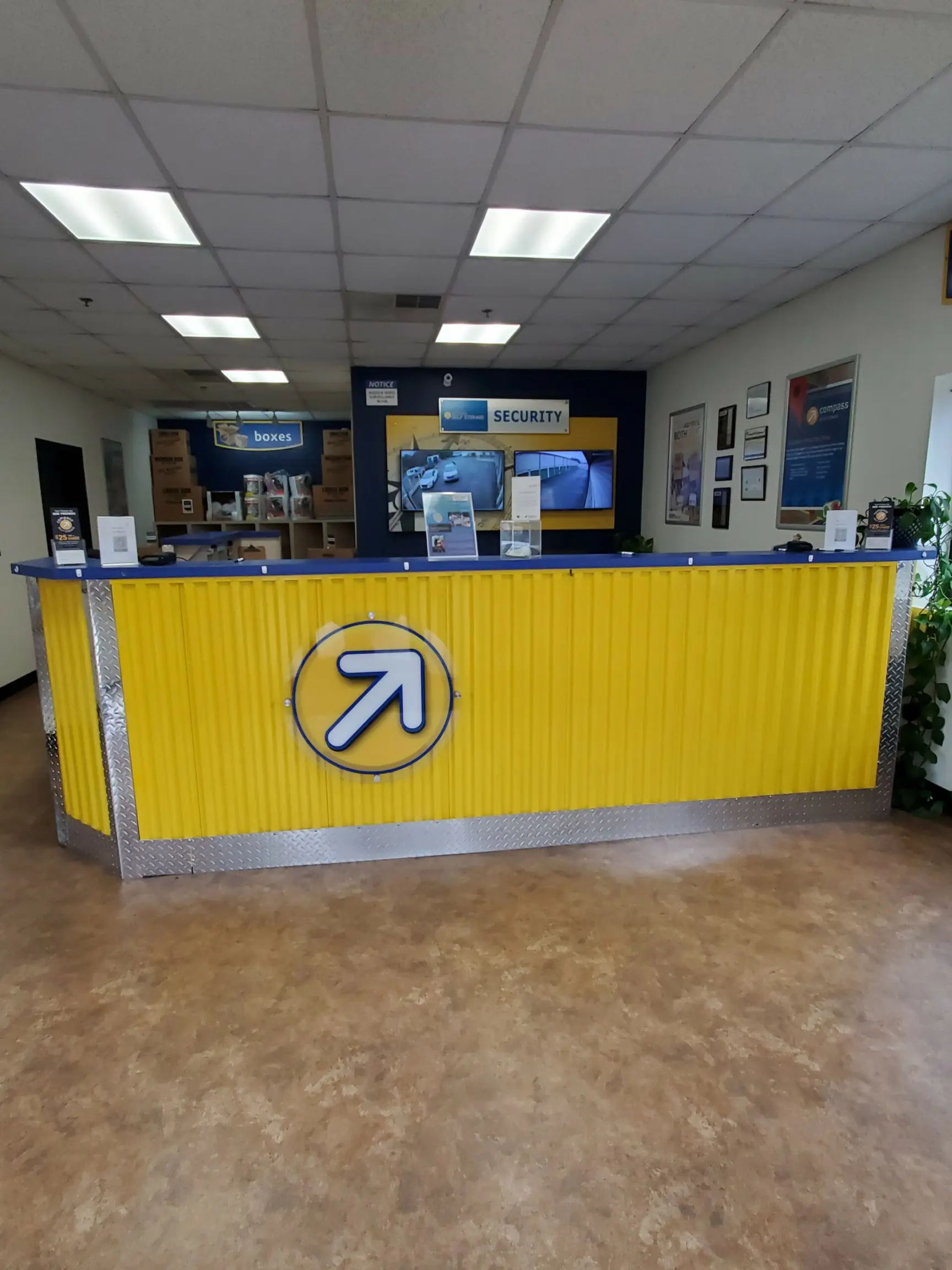 Yellow front desk with security camera footage in the back.