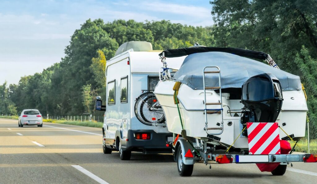 RV towing a boat on the highway.