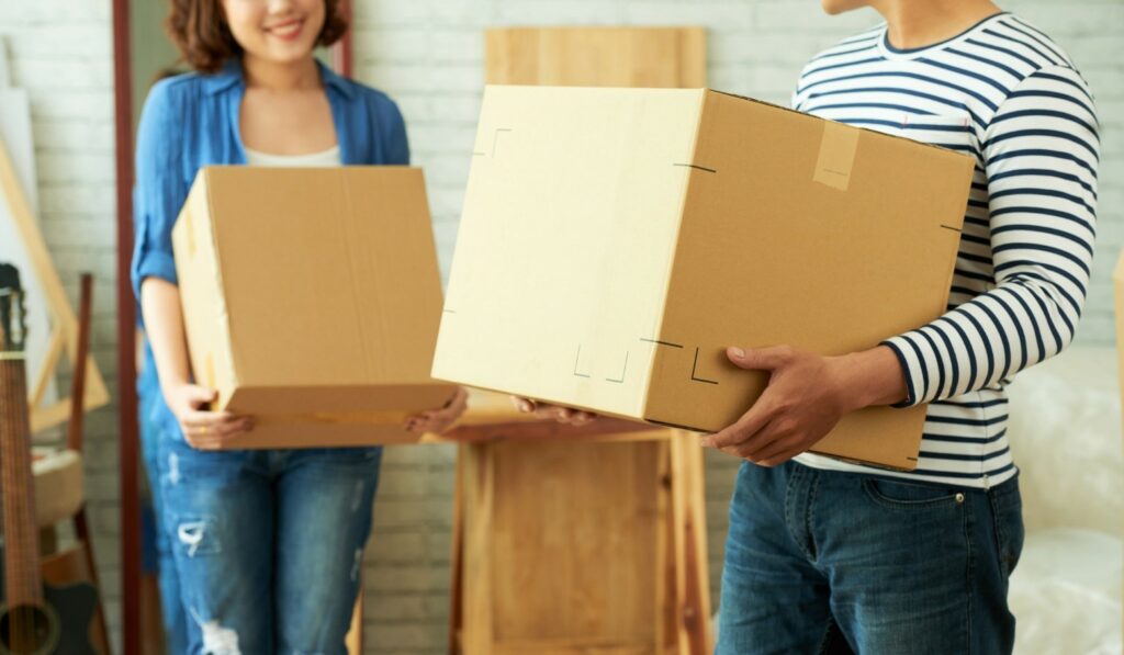 Two people holding moving boxes.