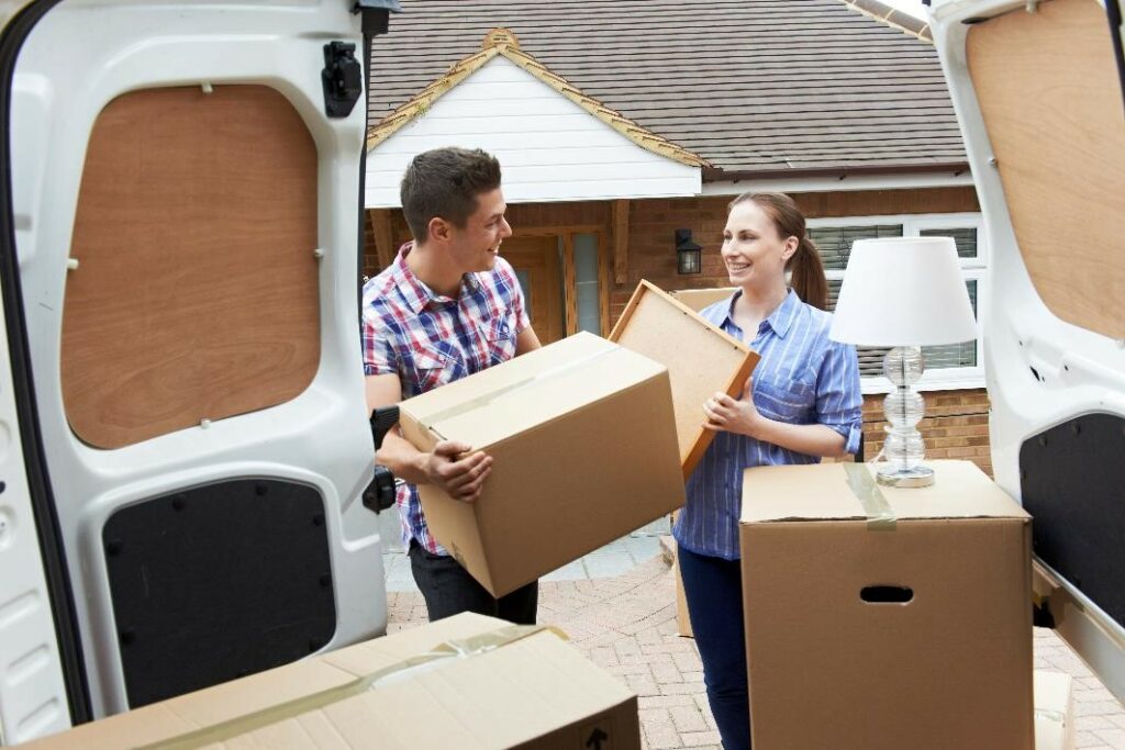 Smiling couple loading moving boxes into a van.