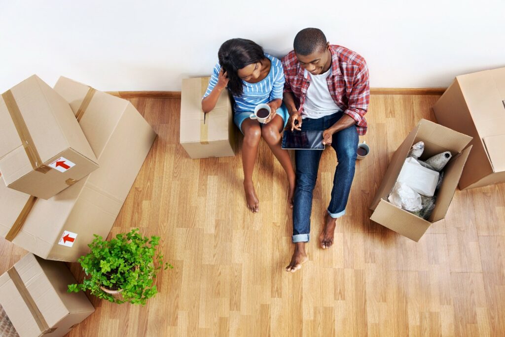 Couple looking at a tablet surrounded by moving boxes.