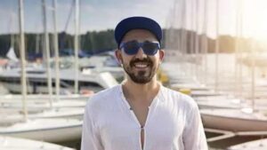 Man smiling in front of a marina filled with boats.