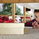 Young boy reaching for a present hidden under a bed.