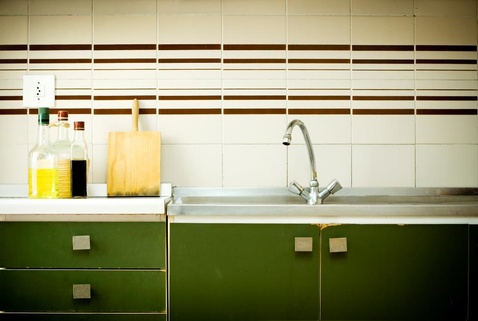 Three cooking bottles and cutting board sitting beside a sink.