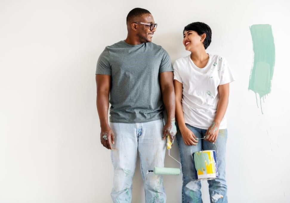 Smiling couple painting a room.