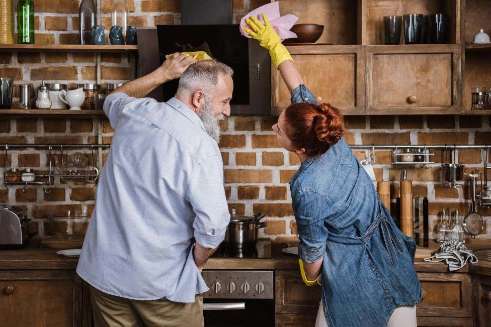 Happy couple cleaning a kitchen.