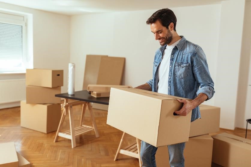 Man smiling while moving boxes out of house.