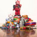 A red robot stands on top of a pile of collectible toys, such as a vintage teddy bear.