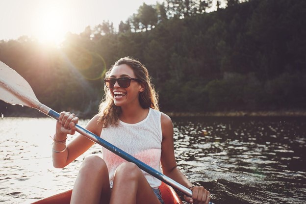 a woman holding a paddle is smiling while kayaking in the water