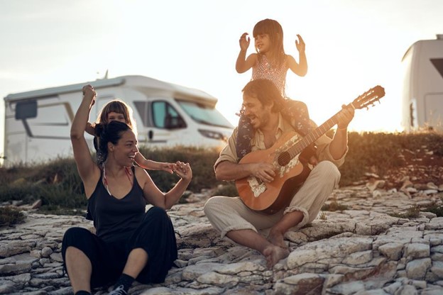 A family with a guitar and an RV