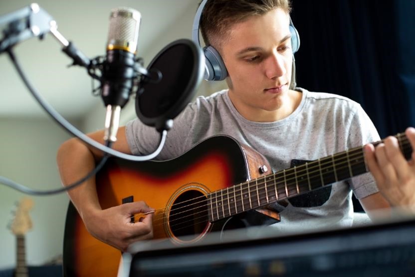 A man playing an acoustic guitar in a music studio