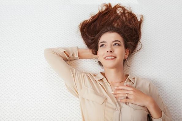 A redheaded woman laying on a mattress