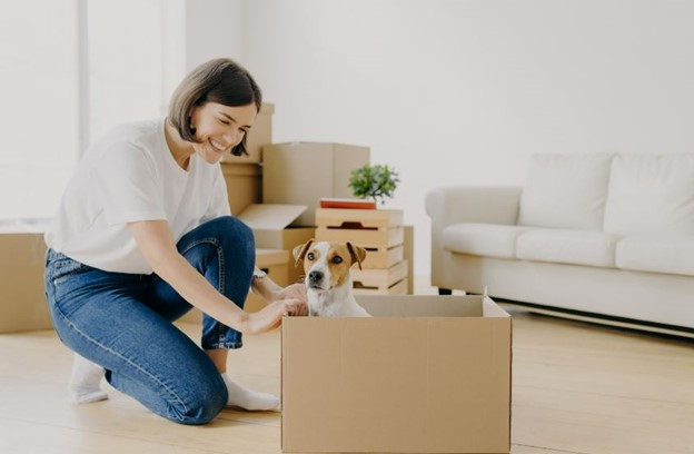 A woman unpacking boxes with her dog
