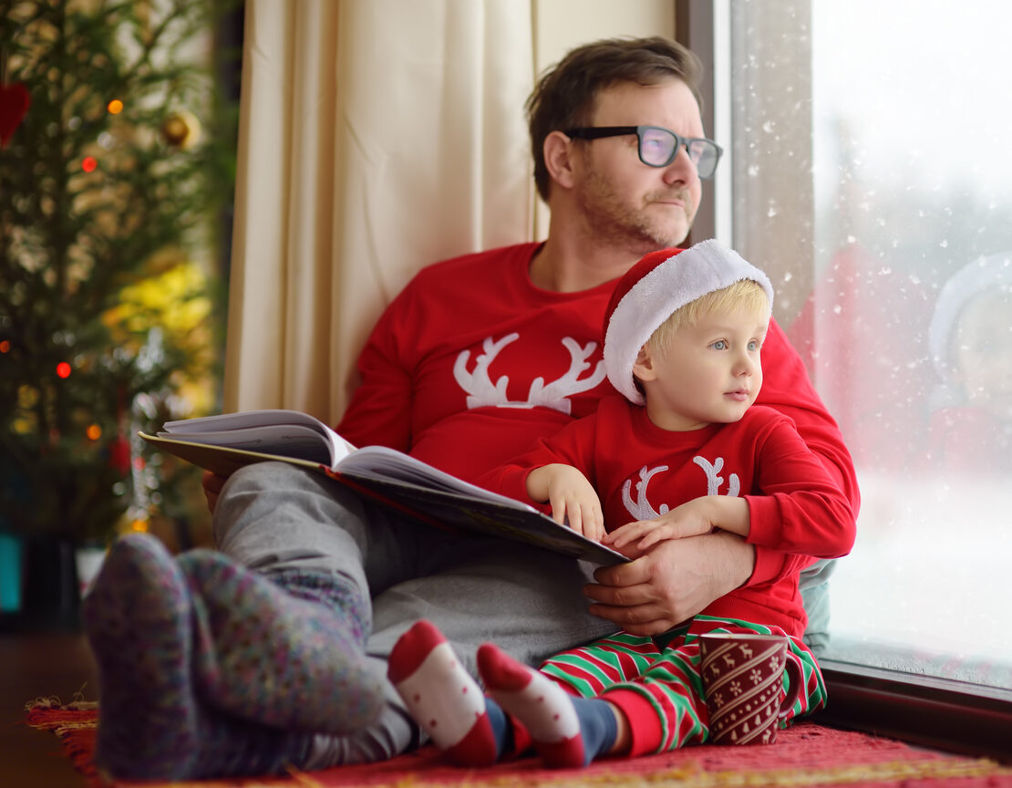 Man holding a baby in Christmas apparel.