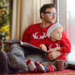 Man holding a baby in Christmas apparel.