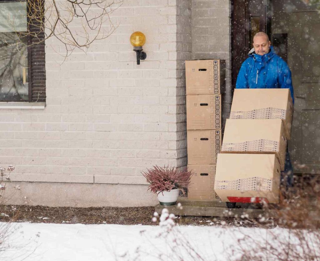 A man maneuvering in the snow with a loaded moving dolly