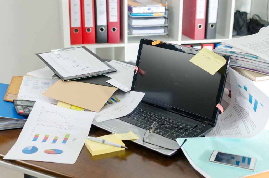 Cluttered work desk with papers and a computer