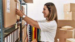 Woman placing a labeled box on shelving unit