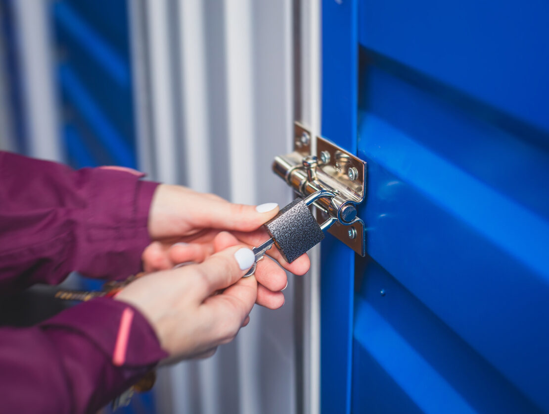 A woman opens a lock on a blue storage unit