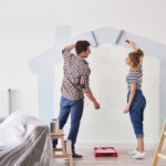 A man and woman painting the walls of their new house.