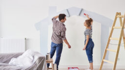 A man and woman painting the walls of their new house.
