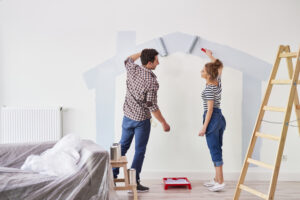 A man and woman painting the walls of their new house.