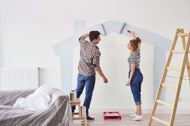 A man and woman painting the walls of their new house.