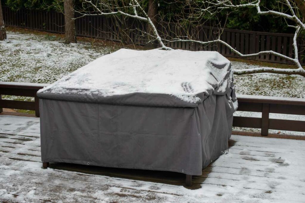 A tarp covers patio furniture to protect from snow