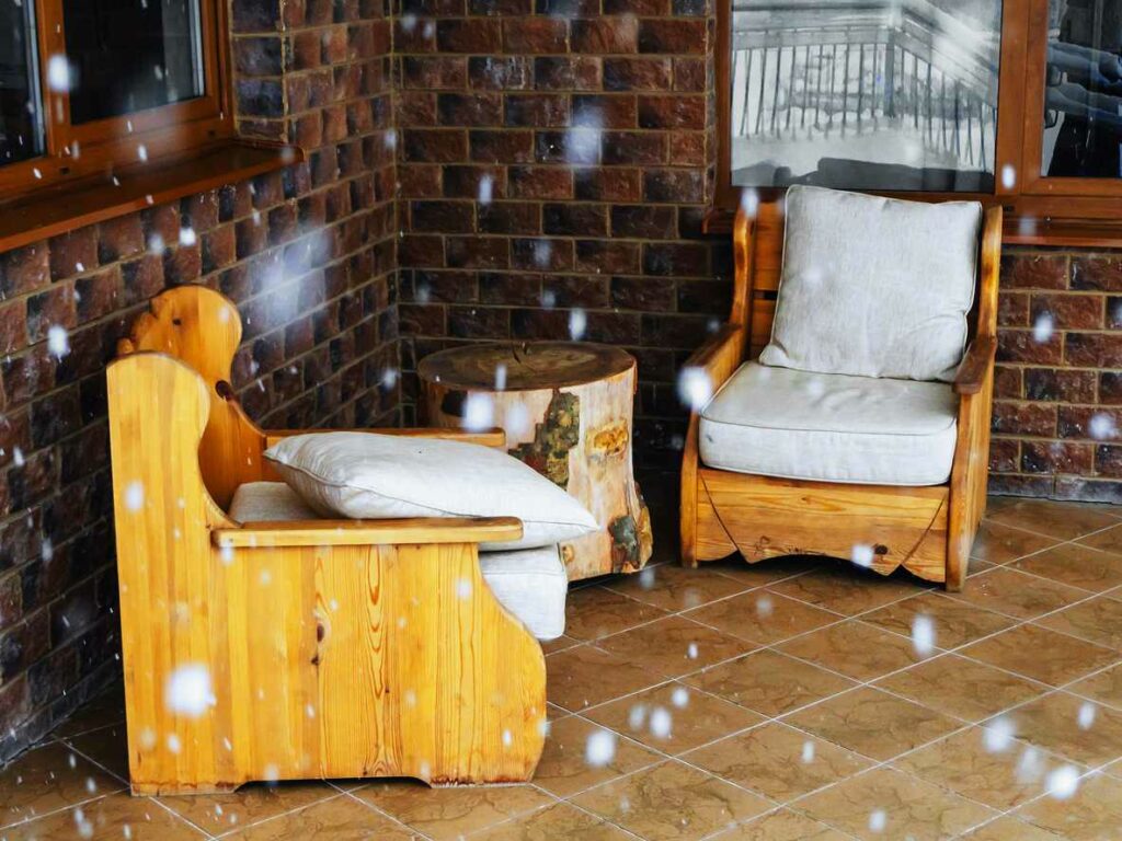 Wooden furniture with cushions slowly getting covered in snow