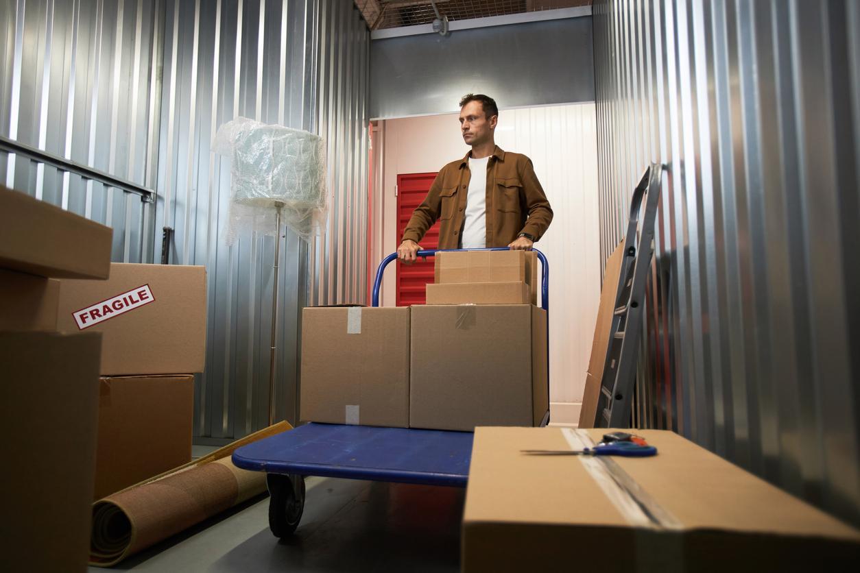 A man unloading boxes from a cart into his self storage unit.