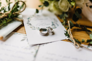 Stylish rings, flowers on wooden table background. Letters from the bride and groom.