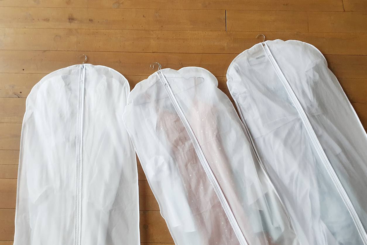 Three wedding dress storage bags lying on a wooden floor, ready to be placed in a unit.