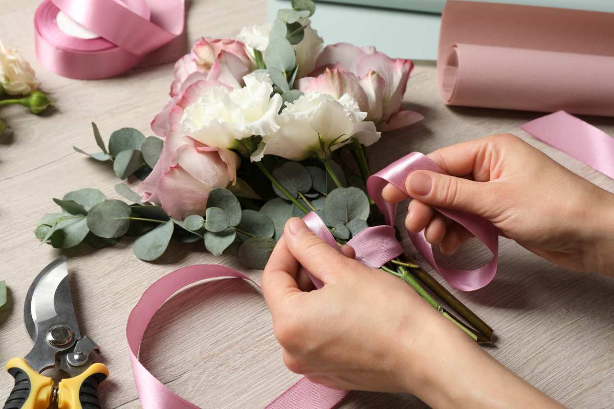 A side view of hands assembling a wedding bouquet.