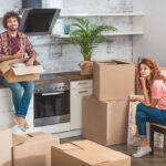 A man and woman unpacking boxes in their kitchen.