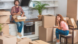 A man and woman unpacking boxes in their kitchen.