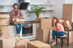 A man and woman unpacking boxes in their kitchen.