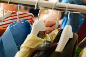 A man grabs a yellow shirt on a hanger in his closet