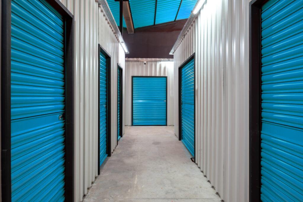 The hallway of a storage facility lined with the blue doors of storage units.