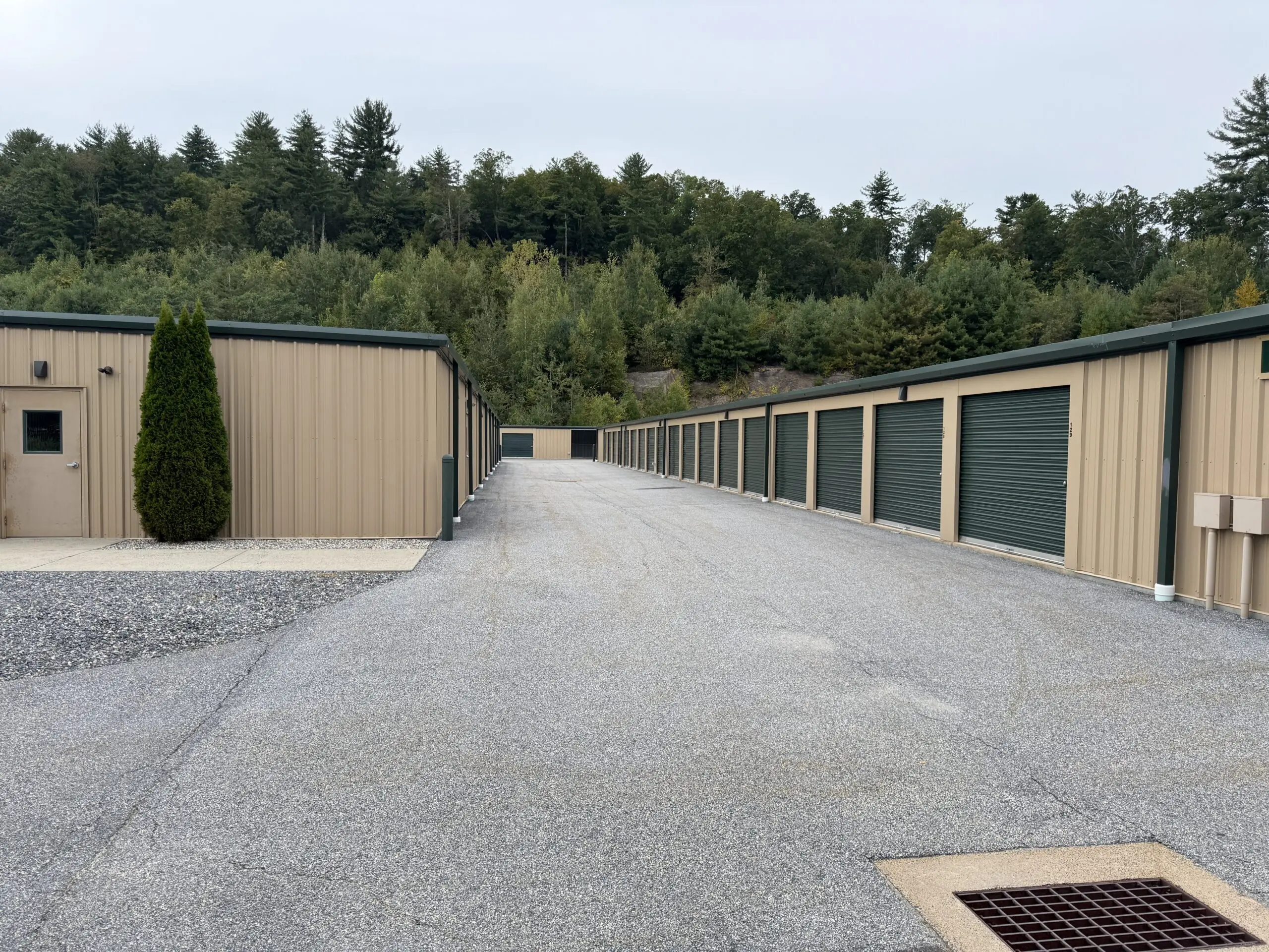 Outdoor drive-up storage units with green doors.
