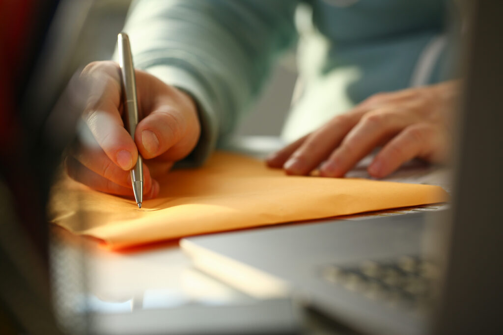 A man writing a forwarding address for his passed loved one’s mail.