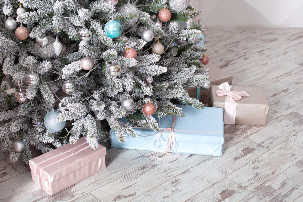 A white Christmas tree decorated with pastel blue, pink, and gold ornaments.