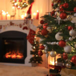 A living room decorated for Christmas with a Christmas tree and roaring fireplace.