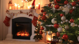 A living room decorated for Christmas with a Christmas tree and roaring fireplace.