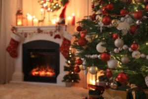 A living room decorated for Christmas with a Christmas tree and roaring fireplace.