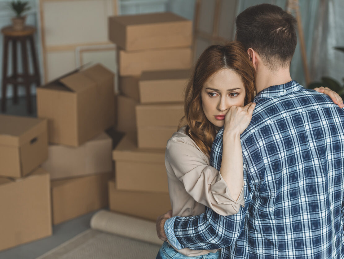 A man and woman hugging while packing up the belongings of a passed loved one.