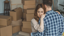 A man and woman hugging while packing up the belongings of a passed loved one.